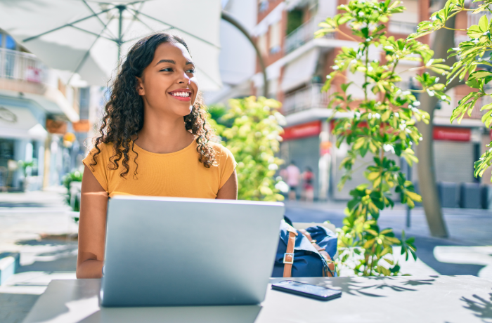 Joven revisando información legal en línea desde su laptop en un espacio exterior.